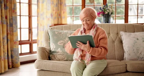 Reading, tablet and relax with old woman on sofa for bingo app, online game or Stock Footage 312274908