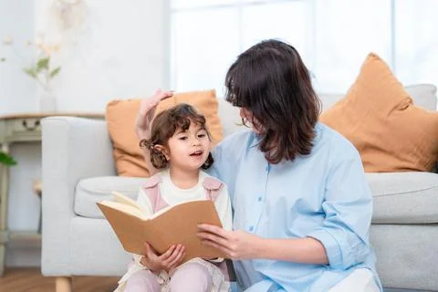 Reading time between a mother and her daughter in a living room with soft l.. Stock Photos
