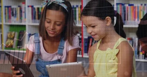 Reading two kids using tablets in library with digital overlays and shelves, in 库存照片