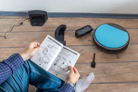 Reading the user guide for robot vacuum cleaner Stock Photos