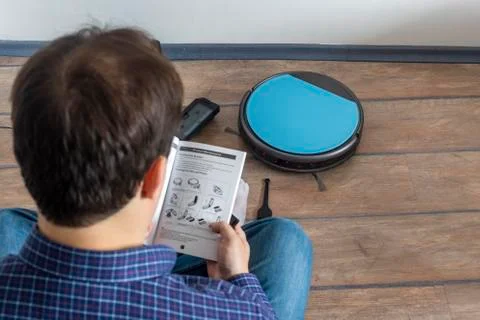 Reading the user guide for robot vacuum cleaner Stock Photos