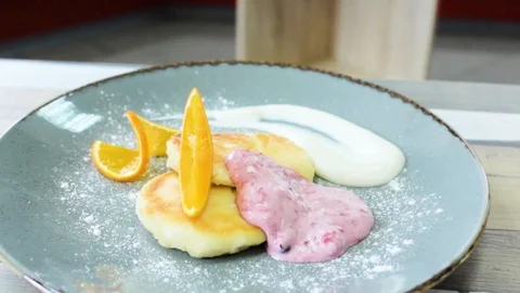 Ready cheesecakes with two sauces and a slice of orange on a plate Stock Footage 112508821