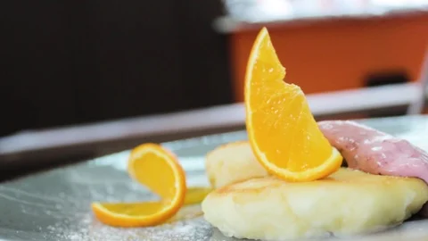 Ready cheesecakes with two sauces and a slice of orange on a plate Stock Footage 112508840