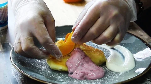 Ready cheesecakes with two sauces and a slice of orange on a plate Stock Footage 112508890