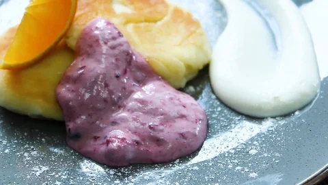 Ready cheesecakes with two sauces and a slice of orange on a plate Stock Footage 112508896