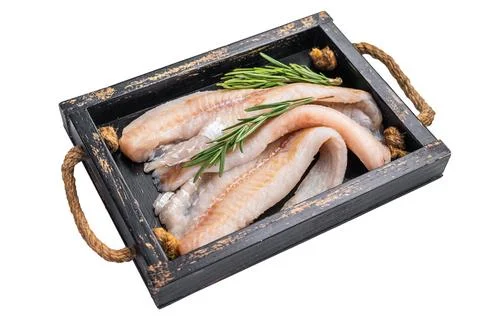 Ready for cooking Raw Hake fish fillets in a wooden tray with herbs isolate.. Stock Photos