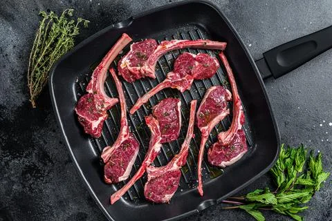 Ready for cooking Raw lamb, mutton chops steaks in a pan with herbs. Black Stock Photos