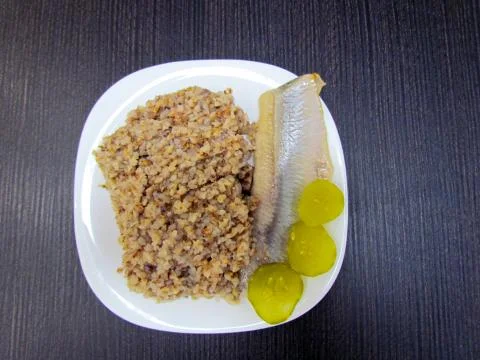 Ready dish which consists of herring, buckwheat and pickled cucumbers Stock Photos