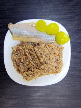 Ready dish which consists of herring, buckwheat and pickled cucumbers Stock Photos