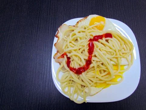 Ready dish which consists of spaghetti, fried eggs with bacon Stock Photos