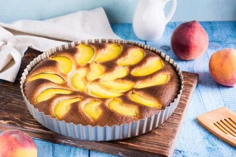 Ready fresh peach pie in a baking dish on the table. Homemade dessert Stock Photos