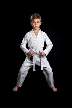 Ready front pose with lowered clenched fists. Kid in brand new white kimono on Stock Photos