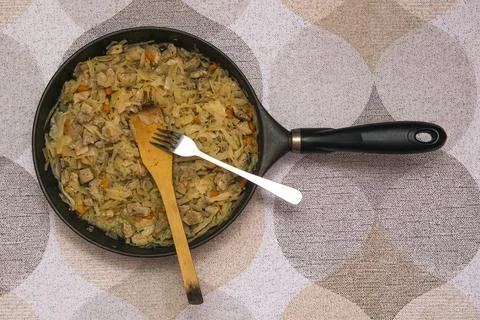 A ready-made dish of cooked stewed cabbage with pork in a frying pan with a w Stock Photos