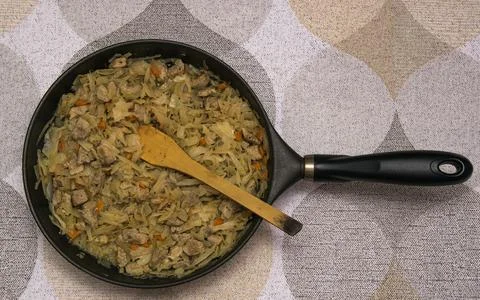 A ready-made dish of cooked stewed cabbage with pork in a frying pan with a w Stock Photos