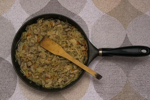 A ready-made dish of cooked stewed cabbage with pork in a frying pan with a w Stock Photos