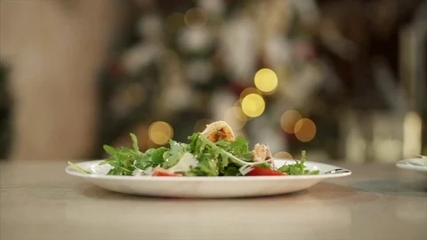 Ready-made festive salad, stands on the table on the background garland Stock Footage 84043046