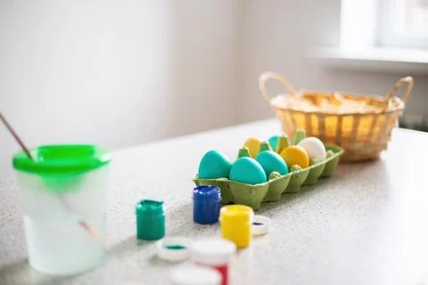 Ready-painted eggs stand on the table with paints and a wicker basket on a .. Stock Photos