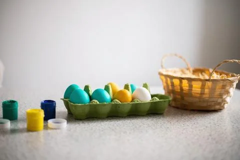 Ready-painted eggs stand on the table with paints and a wicker basket on a .. Stock Photos