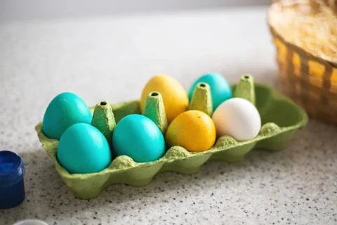 Ready-painted eggs stand on the table with paints and a wicker basket on a .. Stock Photos