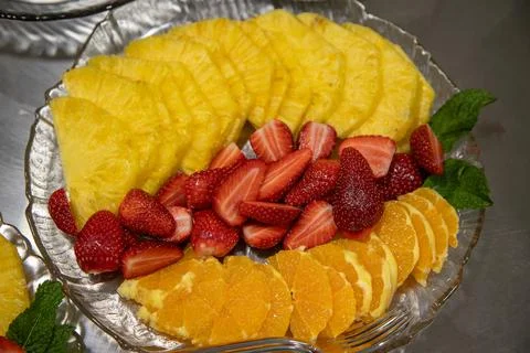 Ready-to-serve sliced fruit platter with pineapple, strawberries, and orange Stock Photos