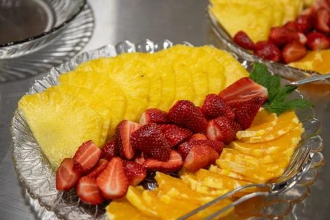 Ready-to-serve sliced fruit platter with pineapple, strawberries, and orange Stock Photos