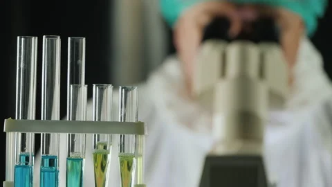 Reagent test tubes in the lab, in the background a man works with a microscope Stock Footage 138122436