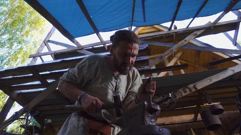Real blacksmith forging the molten metal on the anvil in smithy Stock Footage 108825916