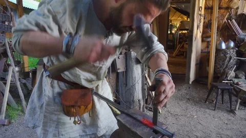 Real blacksmith working with a metal part on stithy in forge. Stock Footage 108825562