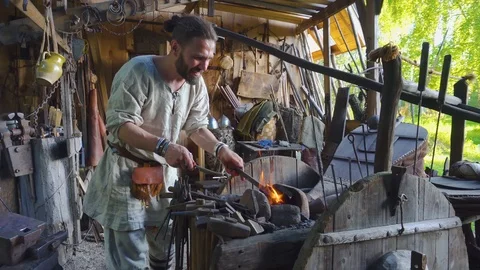 Real blacksmith working with a metal part on stithy in forge. Stock Footage 108825749