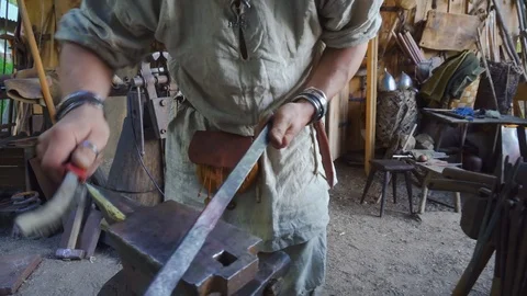 Real blacksmith working with a metal part on stithy in forge. Stock Footage 108825823