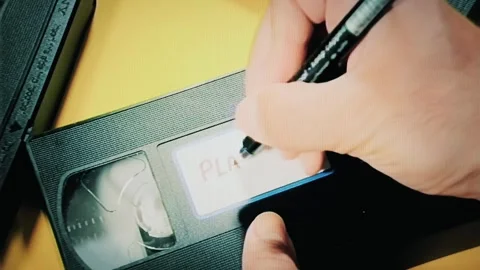 Real capture: hand writes Play Me with black marker on weathered VHS tape Stock Footage 292859467