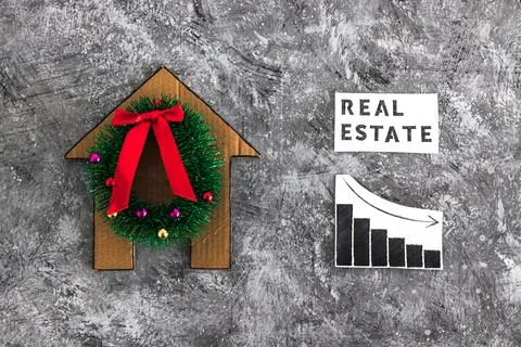 Real Estae text and graph with stats going down next to cardboard house wit.. Stockfoto's