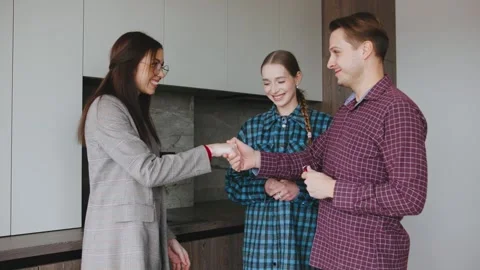 A real estate agent hands the keys to a young married couple, finalizing the Stock Footage 346223916