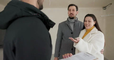 A real estate agent hands over the key to a young woman buying a house with her Stock Footage 260684341