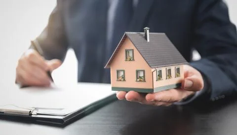 Real estate agent is holding a house model Stock Photos
