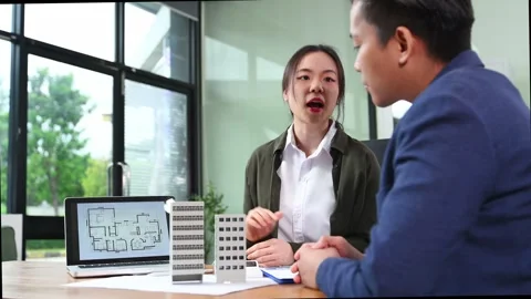 Real estate agent presenting floorplan to client with building models. Busi.. Video stock 312775225