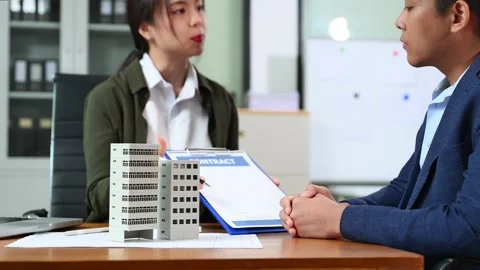 Real estate agent presenting floorplan to client with building models. Busi.. Stock Footage 312775242