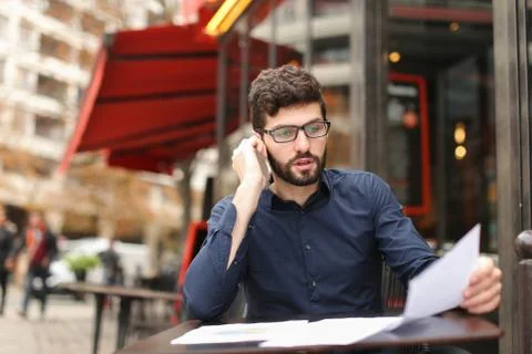 Real estate agent talking with client by telephone at cafe table Stock Photos