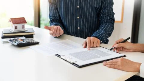 Real estate agents explain the document for customers who come to contact to Stock Photos