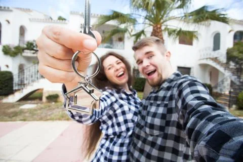Real estate and property concept - Happy couple holding keys to new home and Stock Photos