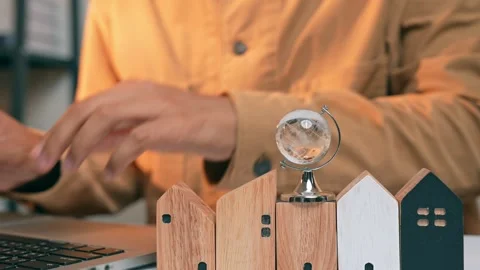 A real estate developer places a miniature globe on a wooden house. Stock Footage 317600563