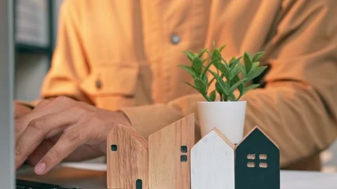 A real estate developer places a small plant on a wooden house. Stock Footage 317600540