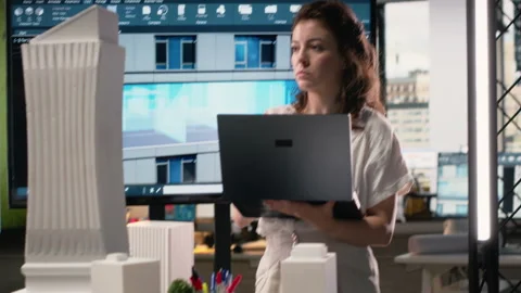 Real estate developer reviewing architectural blueprints and digital 3D models Stock Footage 316794456
