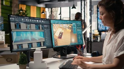 Real estate developer reviews architectural layouts on dual monitors Foto stock