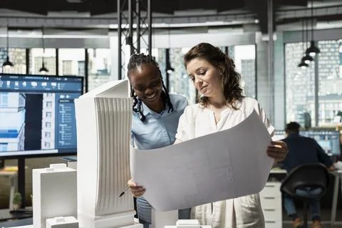 Real estate diverse team analyzing blueprints for construction layout Stock Photos