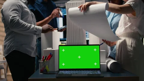 Real estate experts analyzing blueprints and models next to green screen Stock Footage 316644112