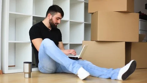 Real Estate. Man With Unpacked Boxes Working At Laptop Stock Footage 96540678