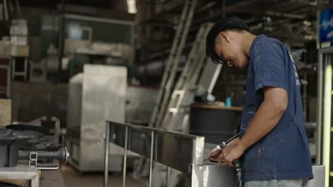 Real factory laborer using a welding gun and smiling to the camera Stock Footage 232585711