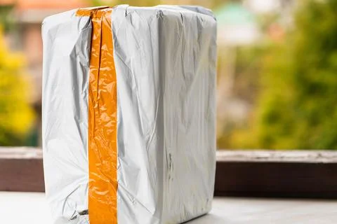 Real postal package, white box with orange stripe with ordered item Stock Photos
