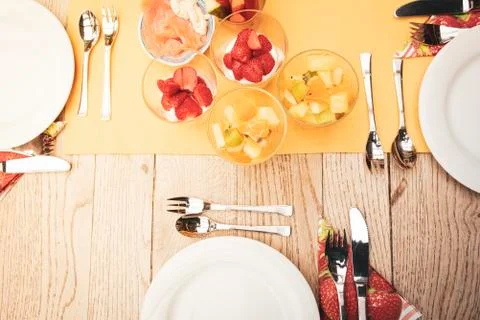 Real set breakfast table with small glass bowls full of fruits and fish, yellow Stock Photos